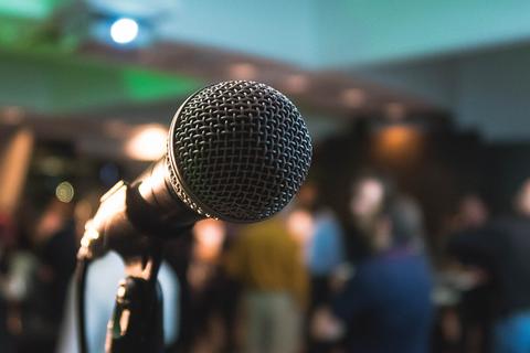 Close-up of a microphone with a blurred audience behind it, singing game Antakshari