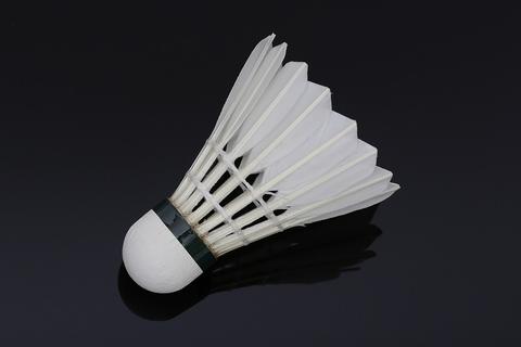 Feather badminton shuttlecock on a dark glossy surface, for Smash Badminton