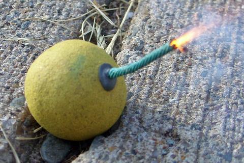 Round yellow firework bomb with a lit green fuse sparking on concrete, Bomb Rush