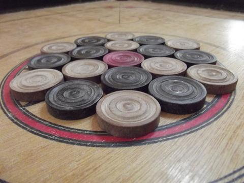Stacked wooden carrom coins arranged on a carrom board centre circle, carrom game