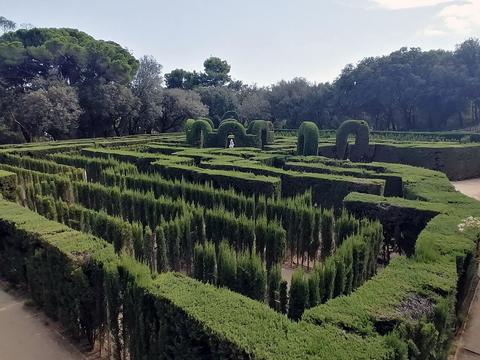Green hedge labyrinth with winding clipped walls and arches seen from above, Chomp maze