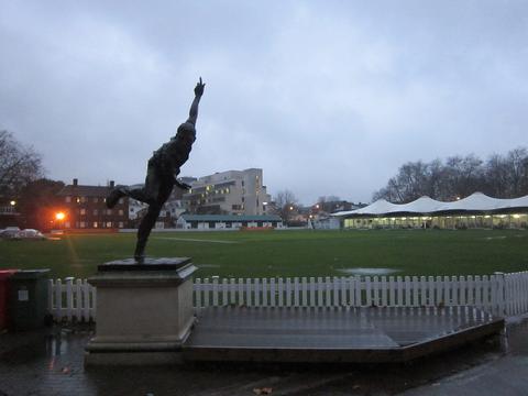 Cricket free online multiplayer game — cricket ground at dusk with a bronze bowler statue