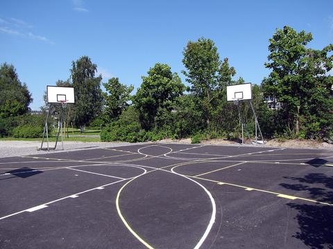 Outdoor asphalt basketball court with two hoops under blue sky, street ball duel