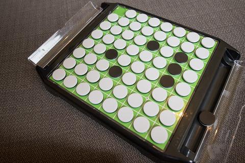 Green reversi board with black and white discs on a fabric surface, Reversi